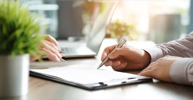 Zwei Personen unterzeichnen Dokumente am Schreibtisch